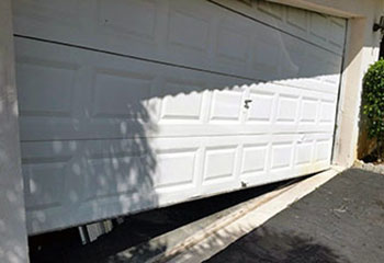 Dented and misaligned white sectional garage door derailed and stuck at a Cicero, IL home.
