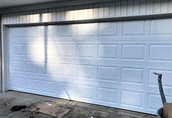 Severely misaligned and fallen sectional garage door before new installation at a Chicago, IL home.