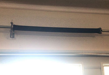 Close-up of a visibly broken torsion spring above a sectional garage door in a Chicago, IL home.